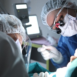 Dental professionals performing dental implant surgery on a patient