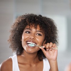 Woman smiling while brushing her teeth