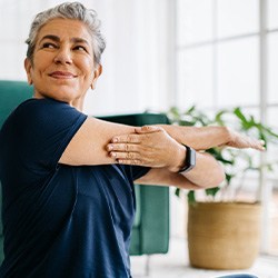 Senior woman smiling while stretching at home