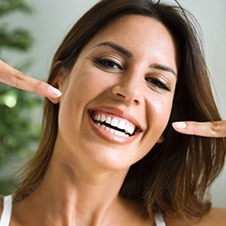 Smiling woman pointing to white, straight teeth
