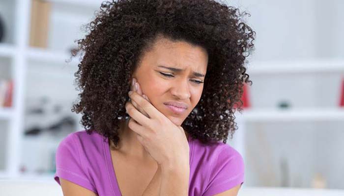 Woman with a toothache in Sweeny holding her cheek