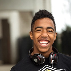 student wearing headphones around their neck and smiling