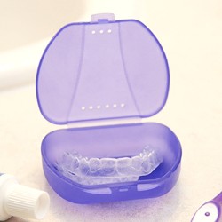 Invisalign aligners sitting in a hard, protective case on a bathroom counter