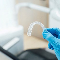 Dentist holding clear aligner with blue glove