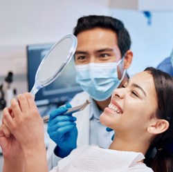 Dentist, dental assistant, and patient smiling at results