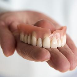 Hand holding a full denture