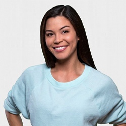 Confident woman with straight teeth standing against gray background