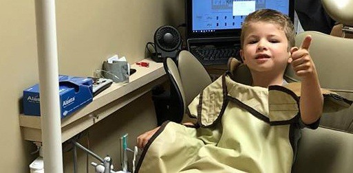 Little boy in dental chair giving thumbs up