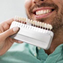 Dentist comparing patient's teeth to shades of enamel