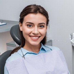 Female dental patient sitting in chair and smiling