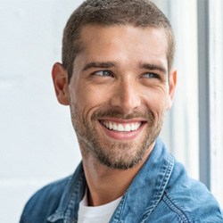 Man in denim jacket looking out window and smiling