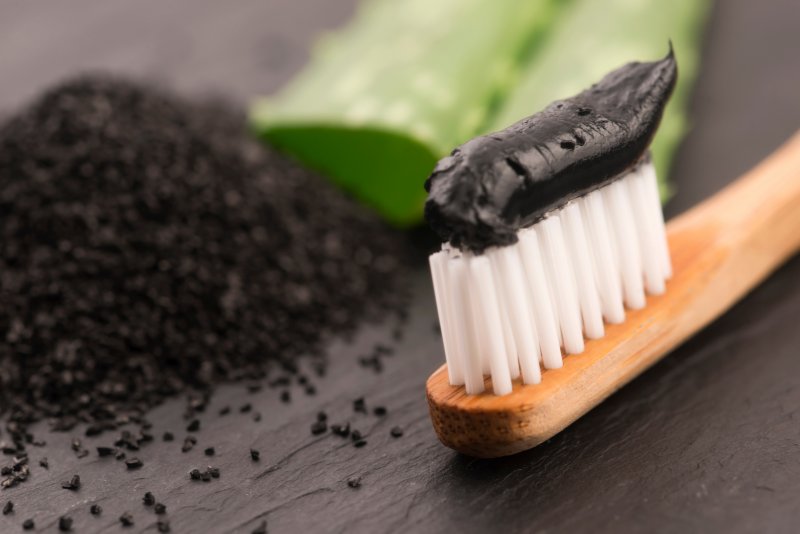 A toothbrush featuring charcoal toothpaste, a danger of DIY teeth whitening