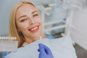 Dentist about to apply veneers to woman smiling in dentist's chair. 